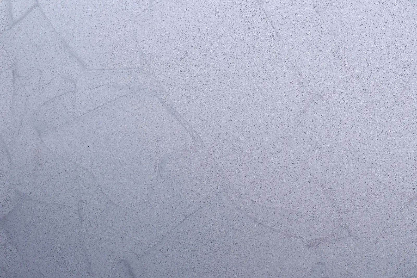 Detail povrchu: svetlý sivý odtieň s jemnou kresbou ťahov hladidla.